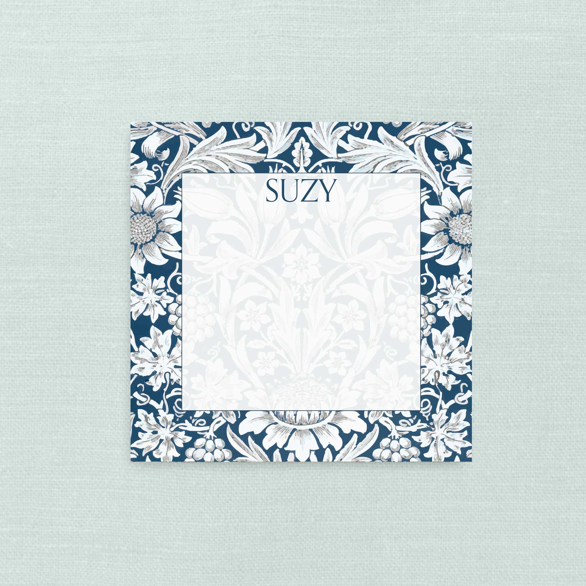 A square personalized notepad with a navy blue and white floral damask border, personalized with the name in navy text.